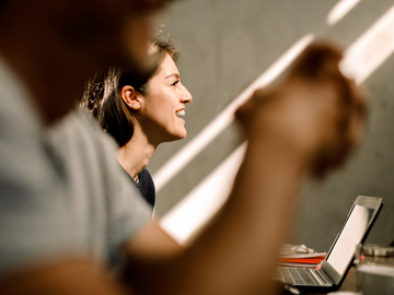 Frau sitzt am Laptop vor einer Betonwand